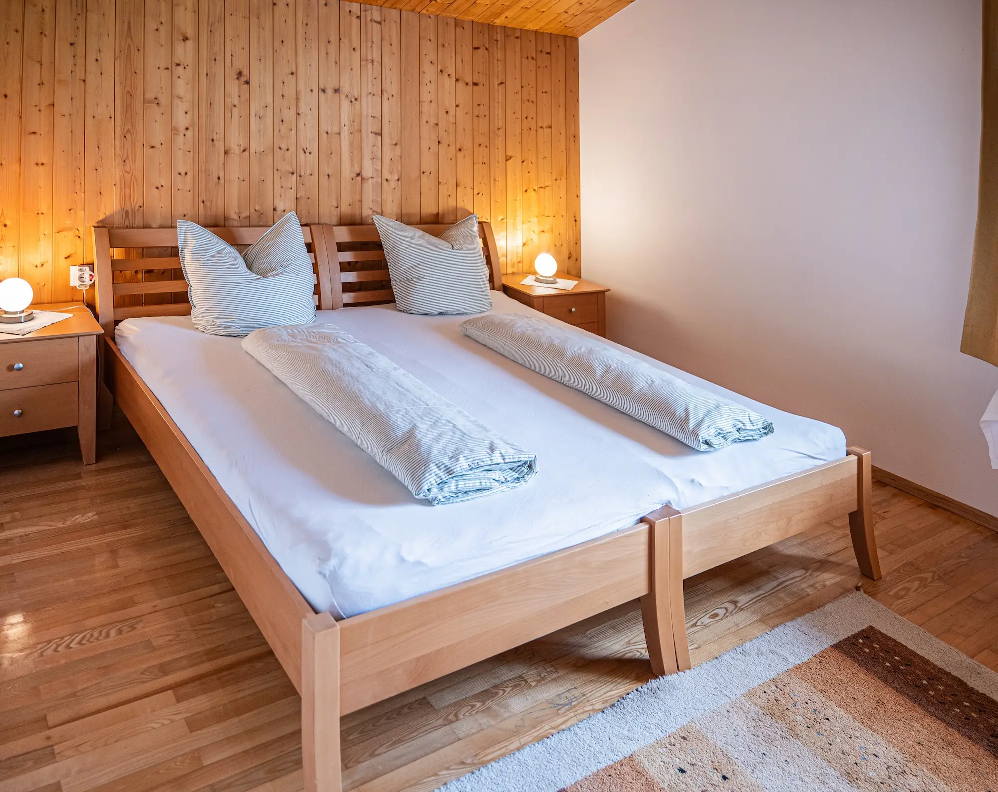Schlafzimmer der Ferienwohnung in Lingenau mit Doppelbett und Holzverkleidung